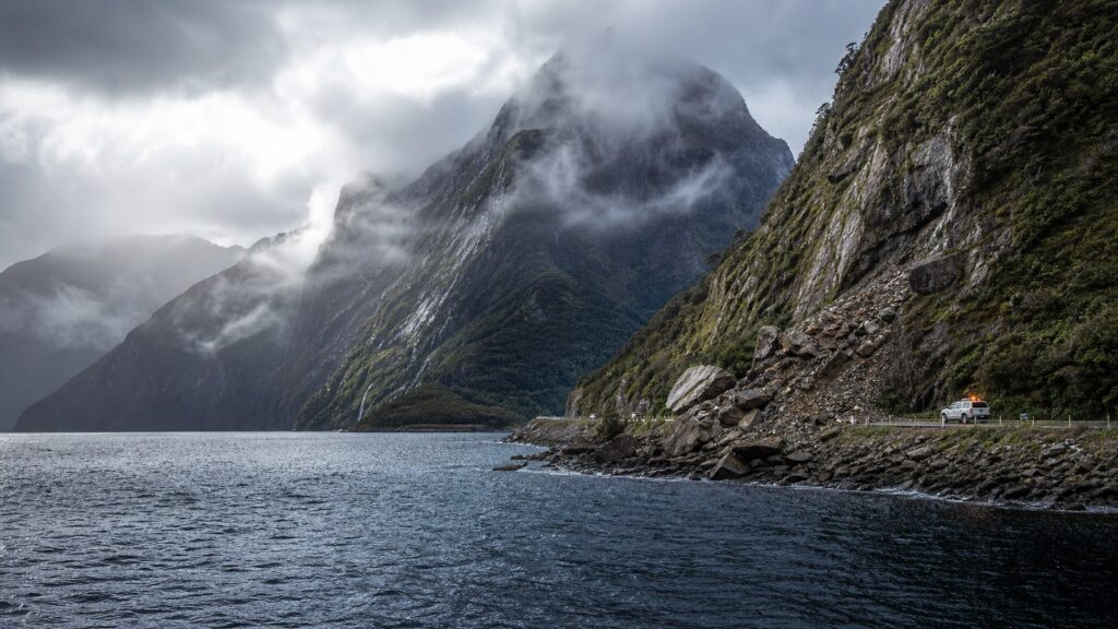 न्यूज़ीलैंड के Fiordland तट और पहाड़ी इलाके का प्रतिनिधि संपादकीय दृश्य, जहां भूकंप के बाद तटीय सतर्कता लागू हुई।